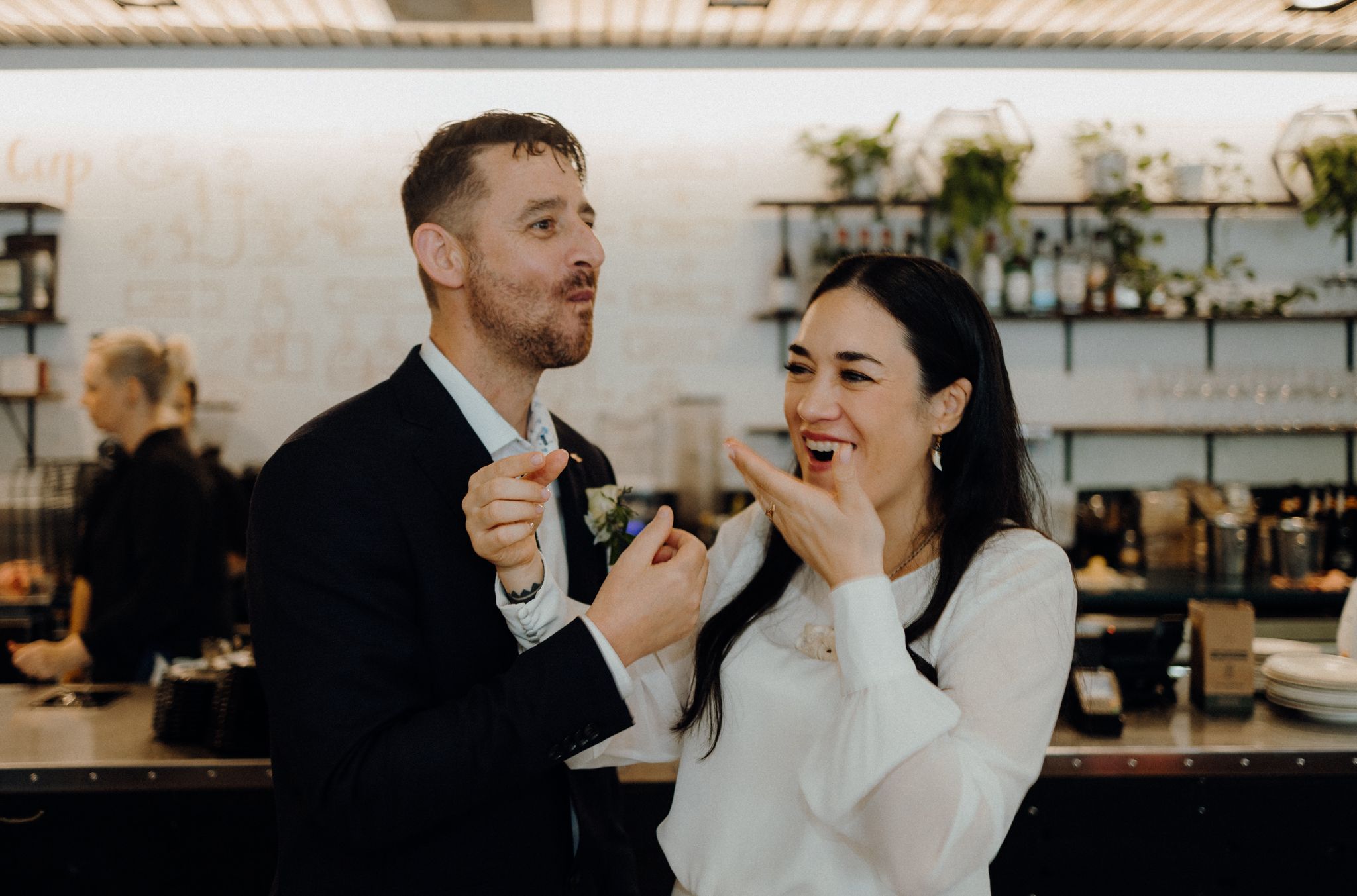 Candid moment of joyful laughter during wedding cake tasting at reception.