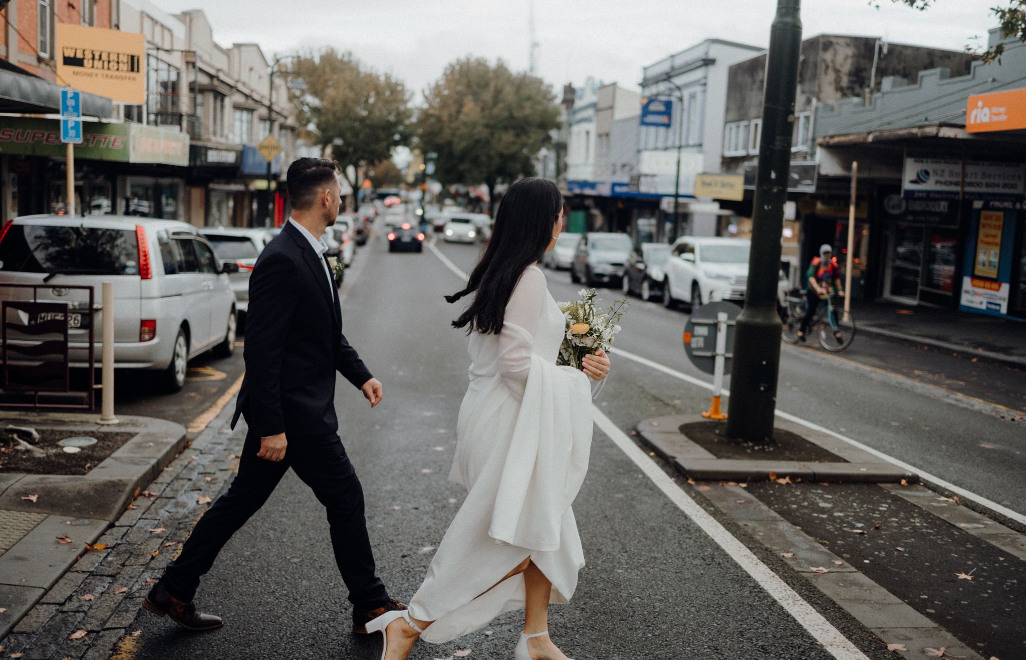 A couple crossing a city street together on their wedding day.