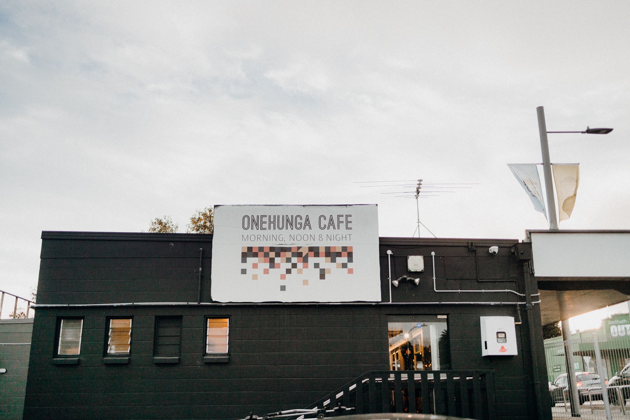 View of Onehunga Cafe exterior with black walls and industrial design.