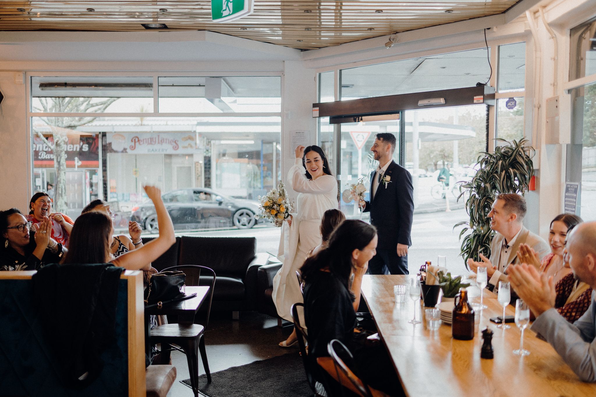 Wedding celebration in a bright cafe space with guests seated at tables.