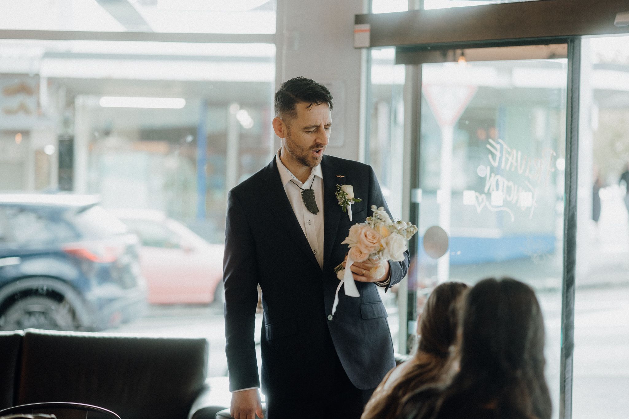 Wedding guest speaking to others during reception at modern cafe venue.
