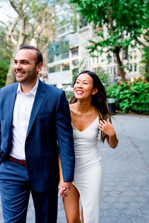man in navy suit and woman in white dress walking through Flatiron District NYC