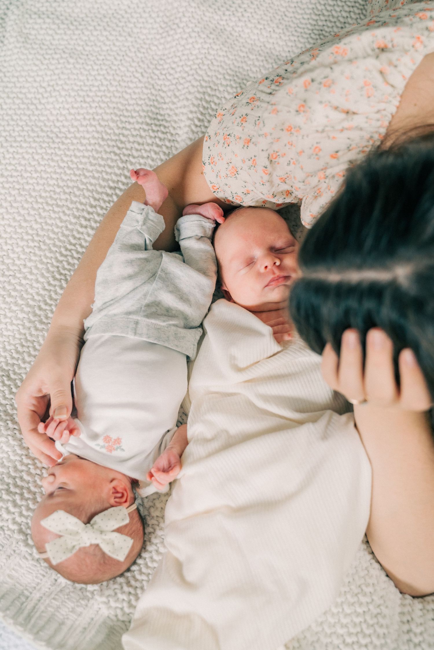 A sleeping newborn baby in light clothing on textured white bedding.