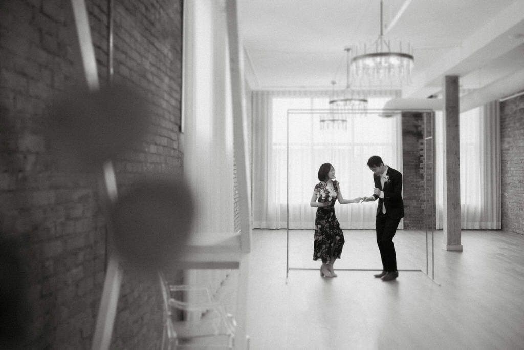 Black and white photo of two silhouettes in an elegant hallway with natural light streaming in.