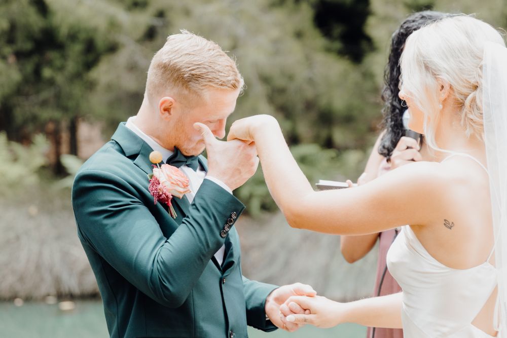 Tender moment shared during wedding ceremony in emerald green and white attire.