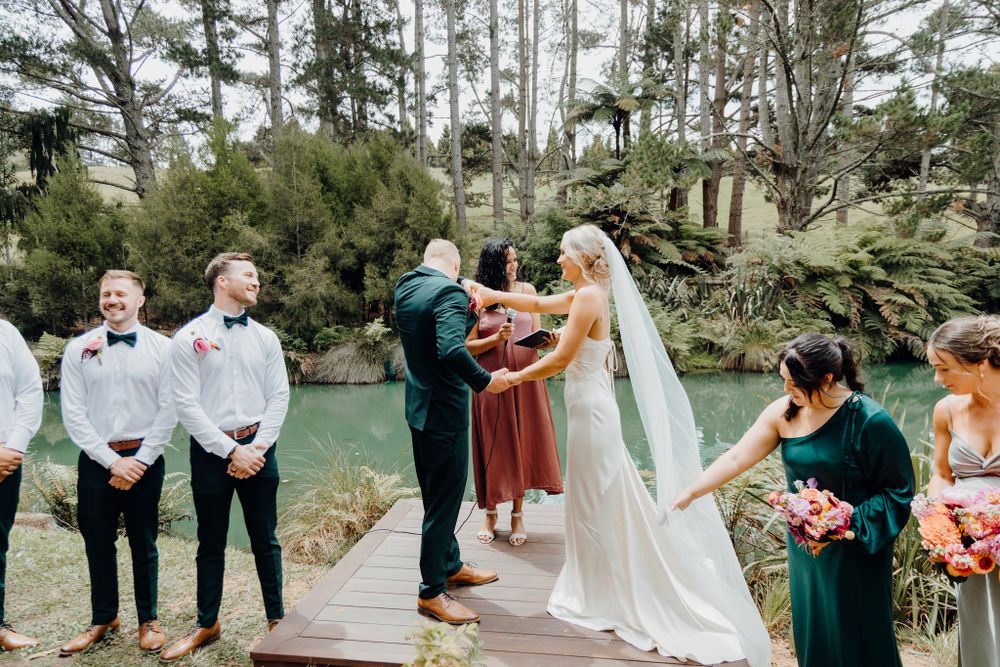 Outdoor wedding ceremony takes place on wooden deck surrounded by tall pine trees.