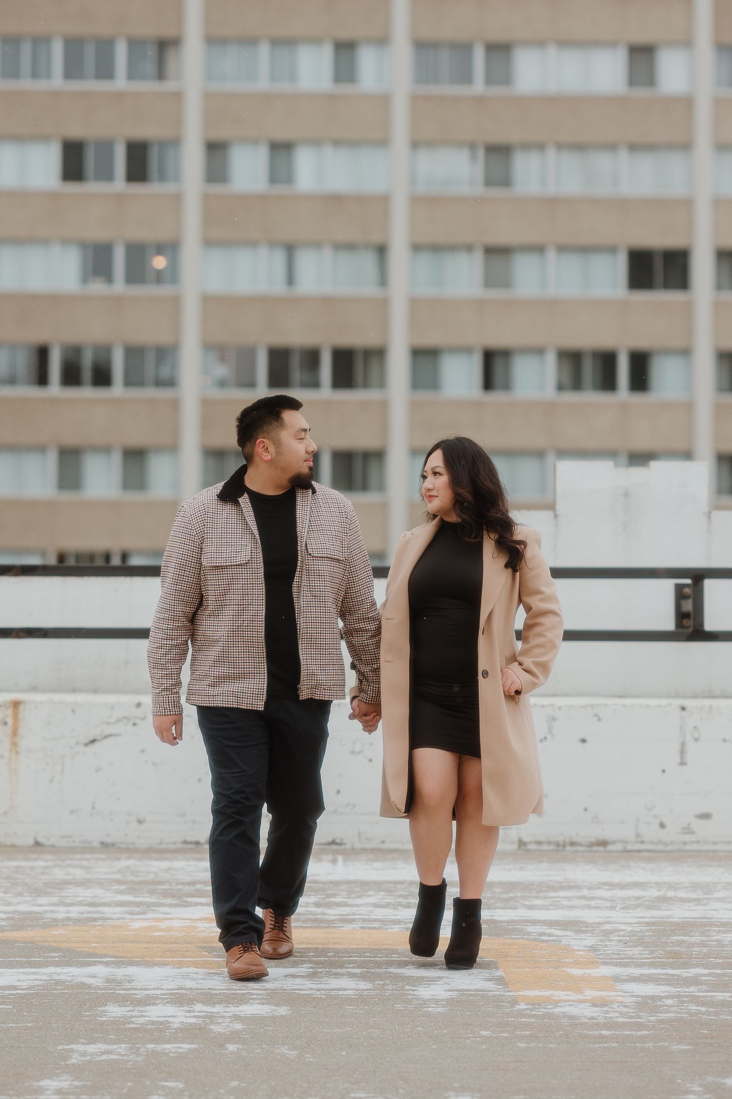 A couple walks together on a rooftop in coordinated casual winter outfits.