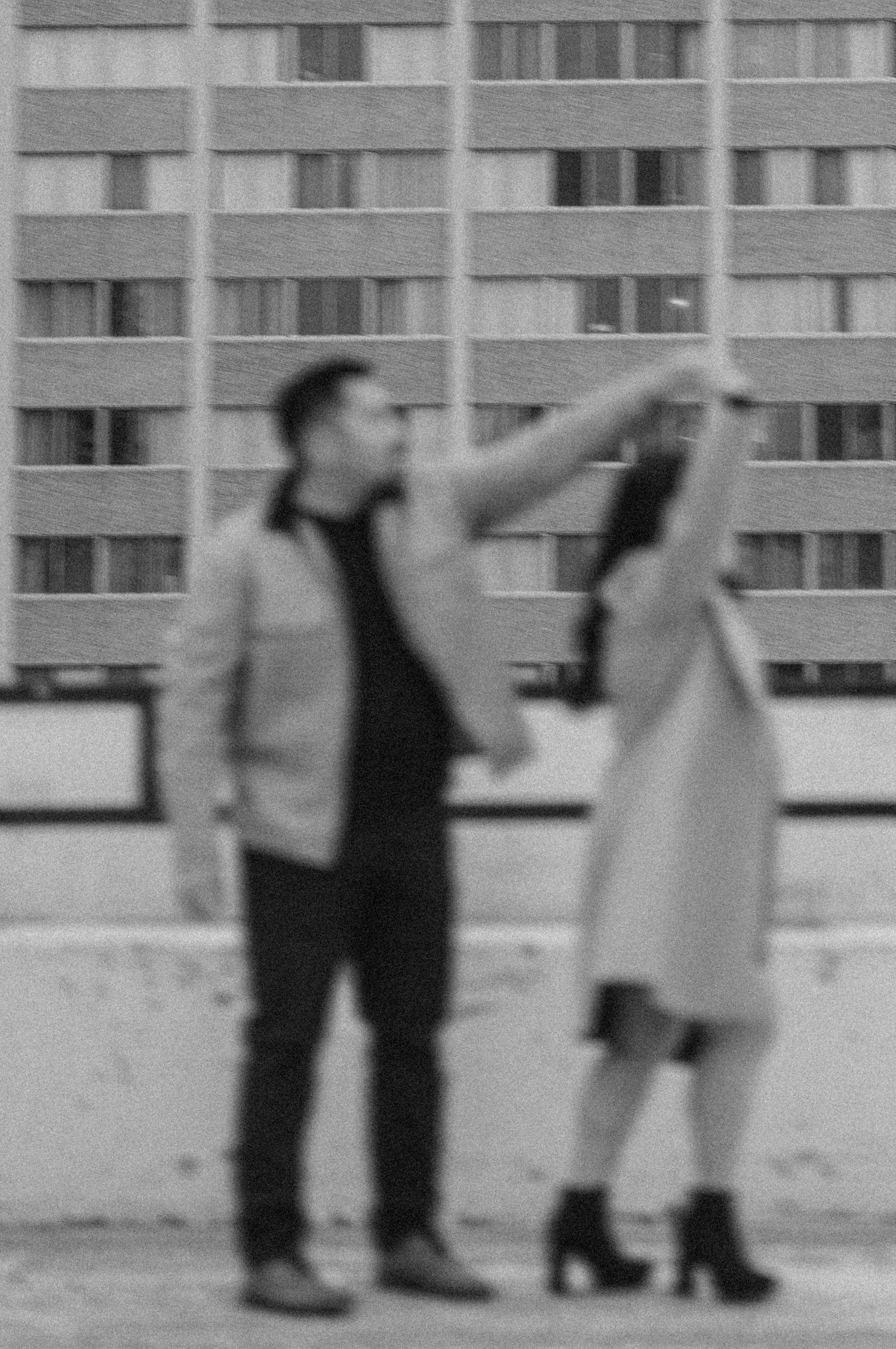 A blurred artistic photo of a couple dancing on an urban rooftop.