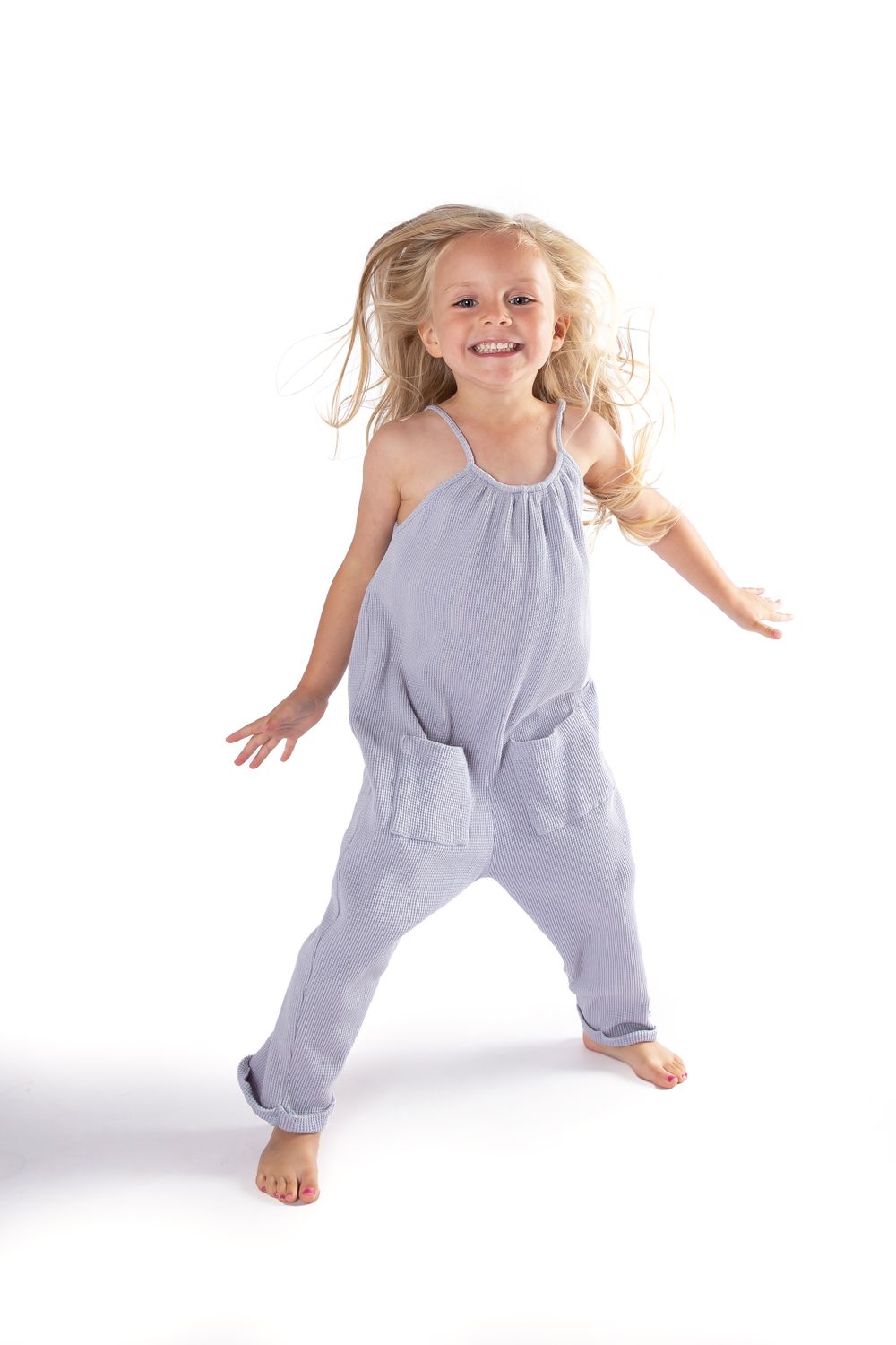 child model in grey jumpsuit jumping on white background
