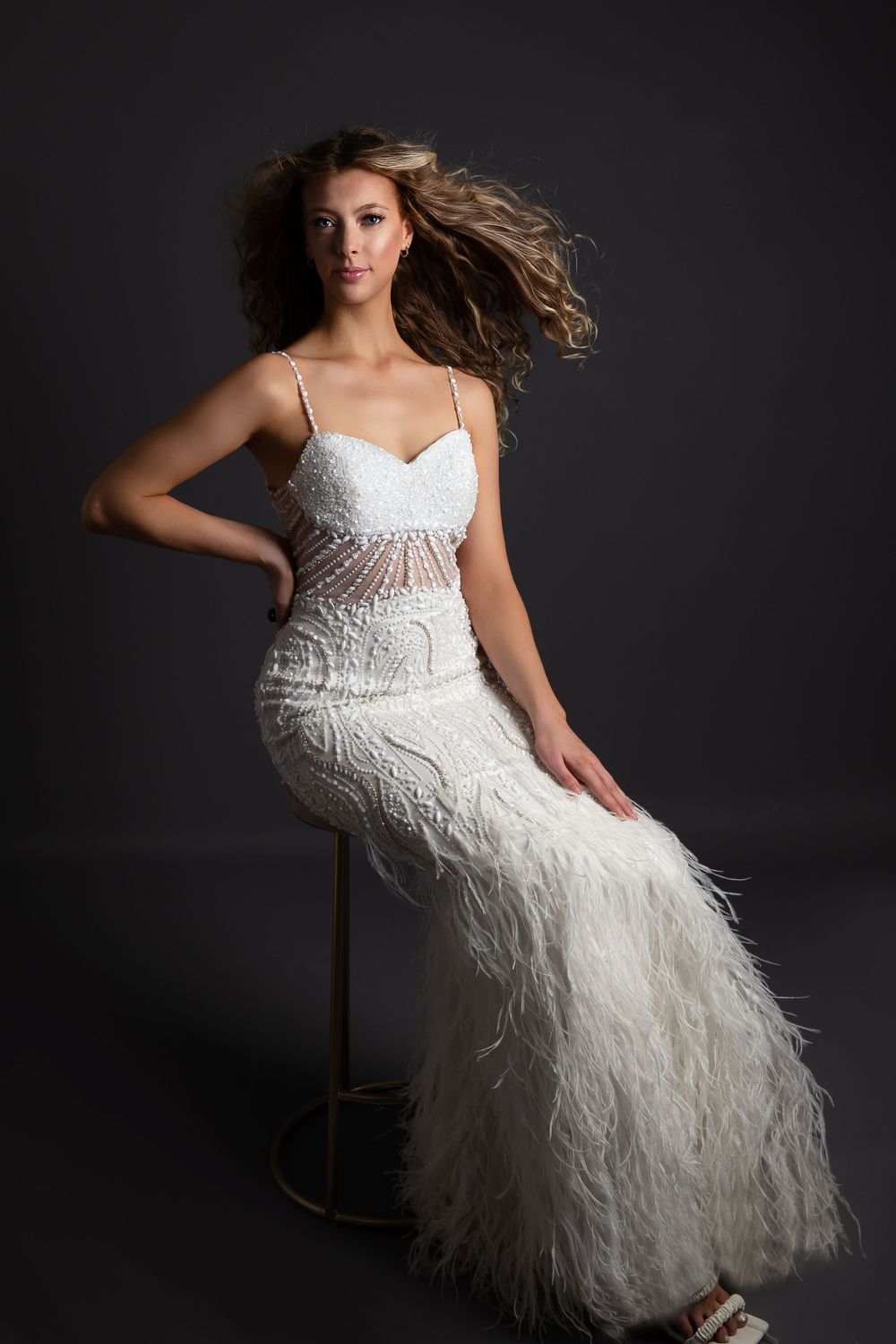 model sat down wearing a white dress with hair wafting