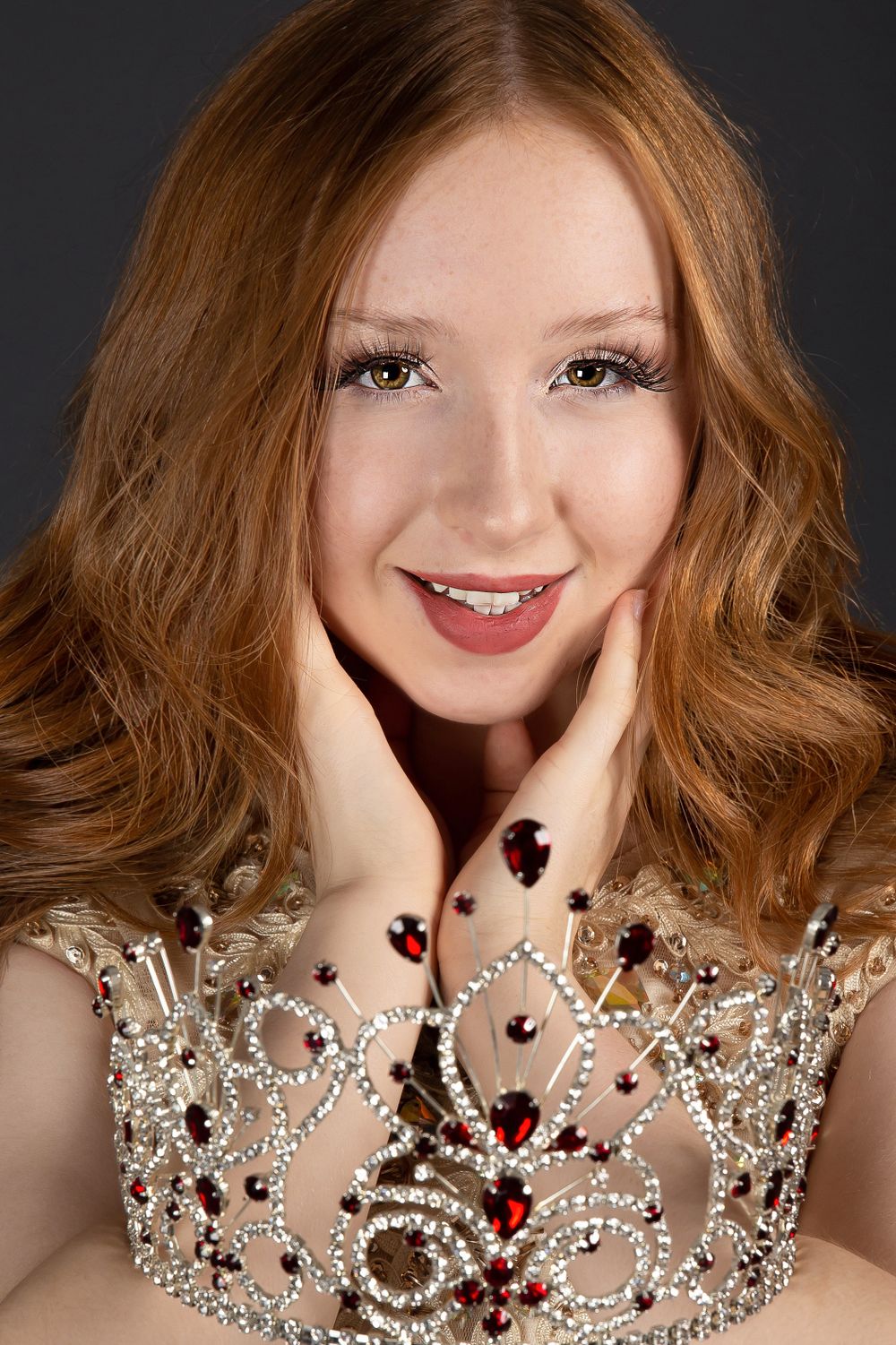 teen pageant queen headshot with crown over her hands