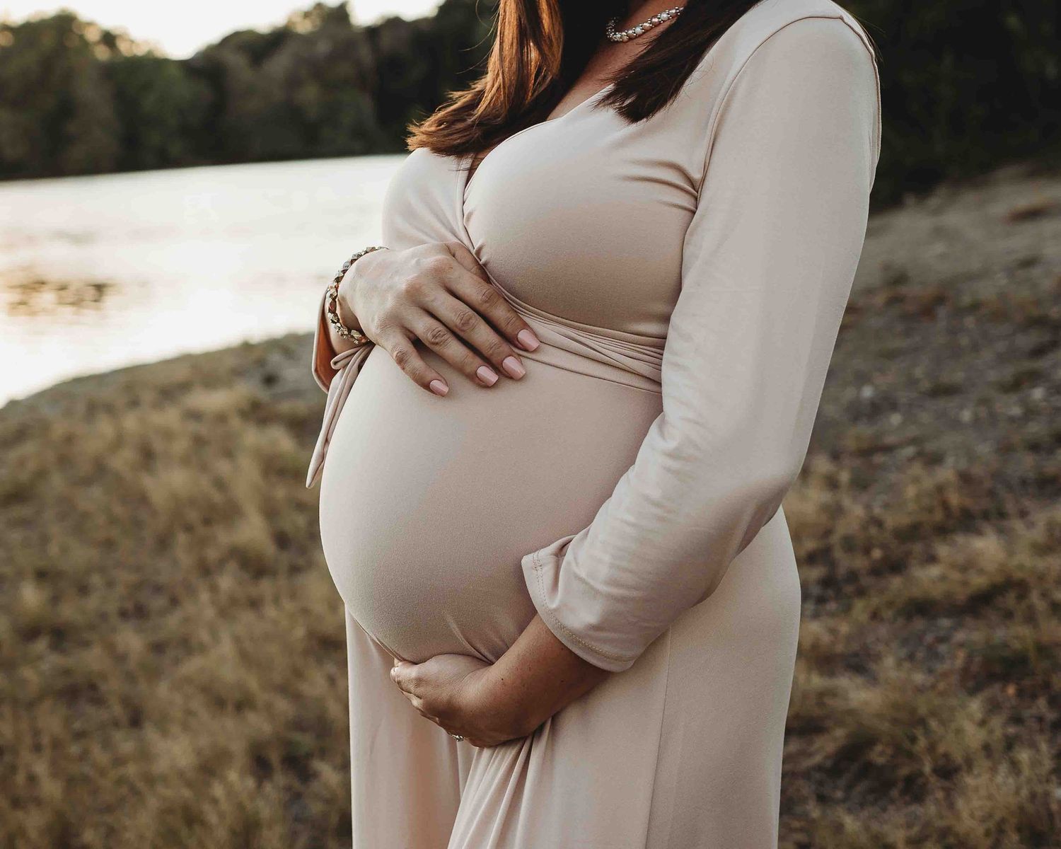 cream maternity dress summer by the water photoshoot hands on belly pictures