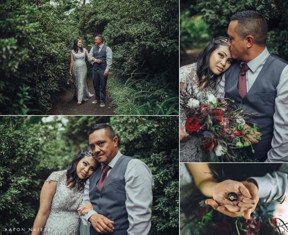 gride and groom standing on a trail surrounded by green florals kissing