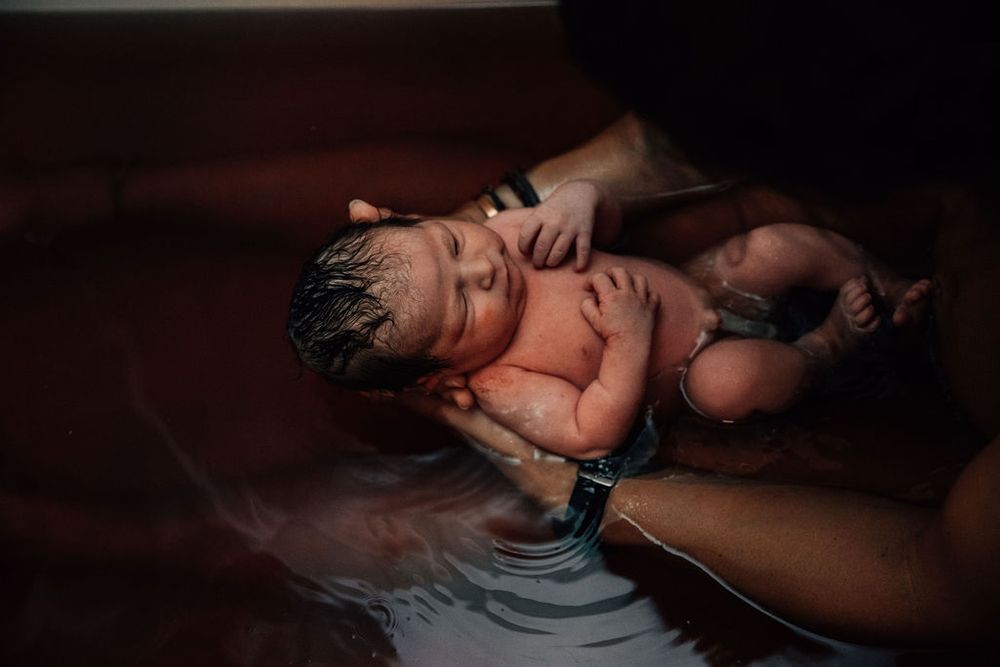 Baby born at home relaxes in an herbal bath