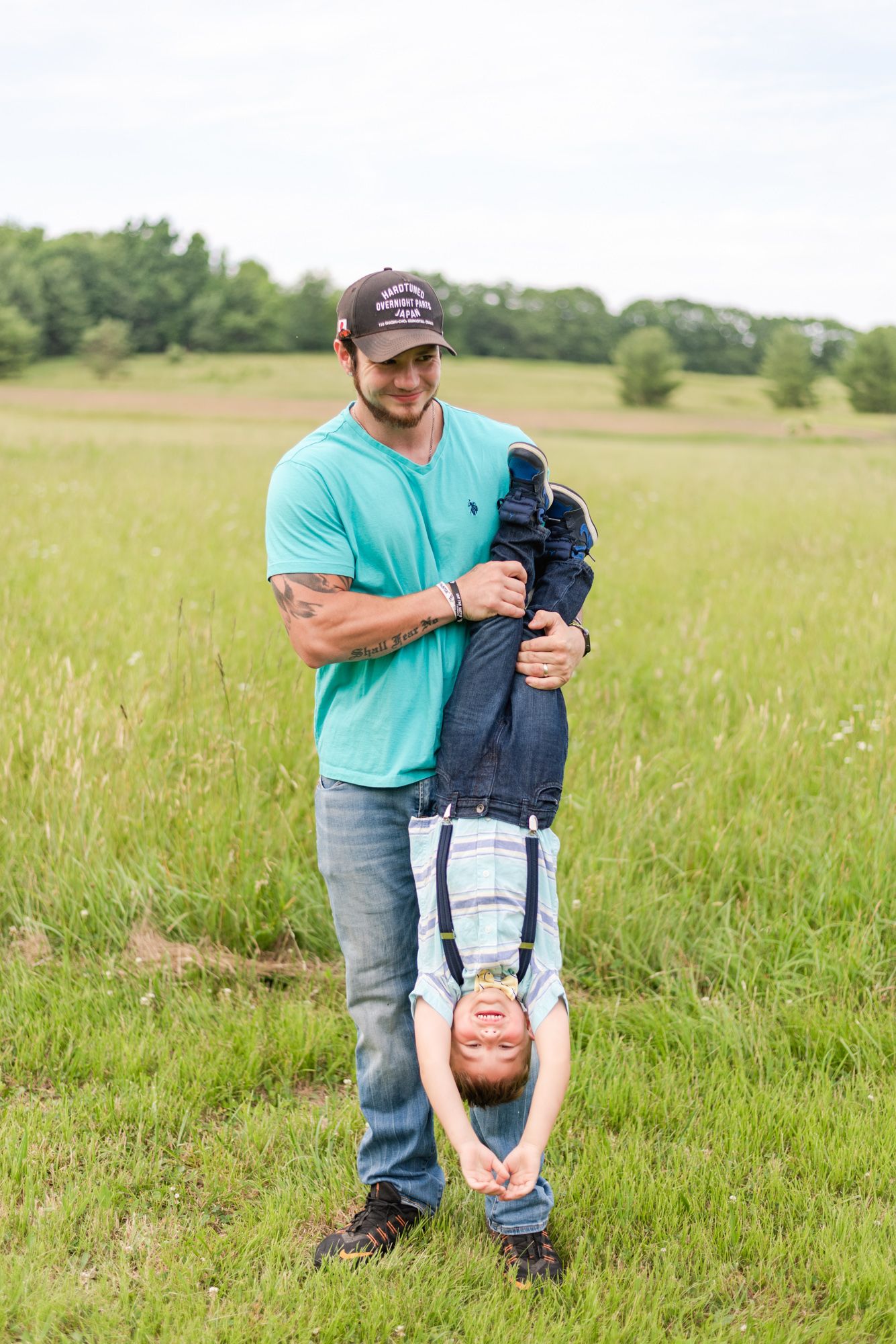 Dad holding boy upside down in field in Clarion Pennsylvania