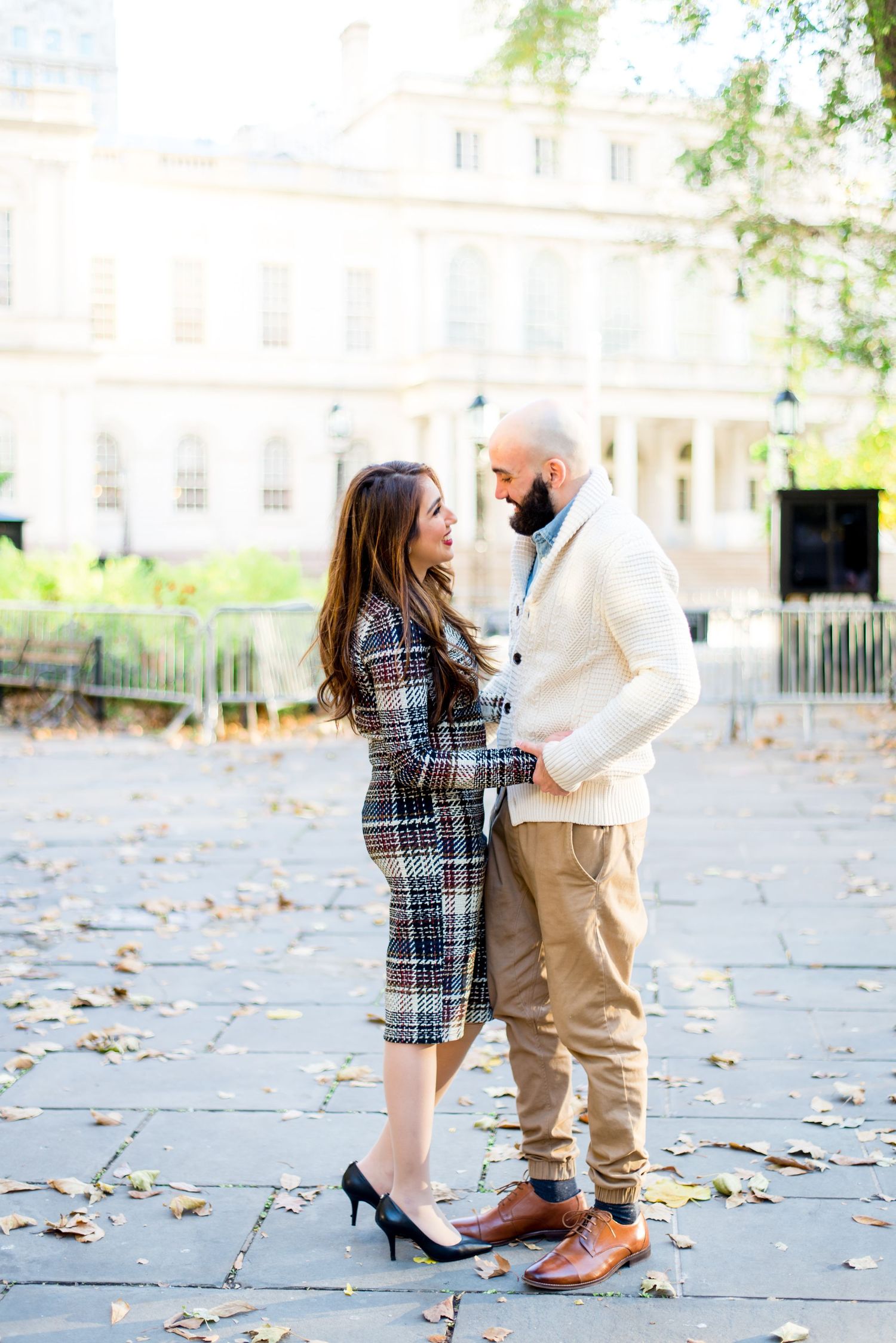 young engaged couple holding hands and smiling at each other at NYC City Hall for engagement pictures