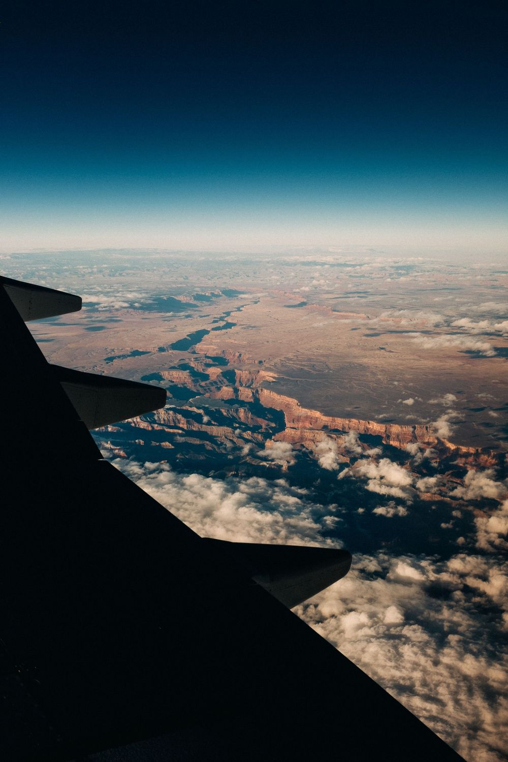 Aerial view of desert canyons and landscape from airplane window during flight.