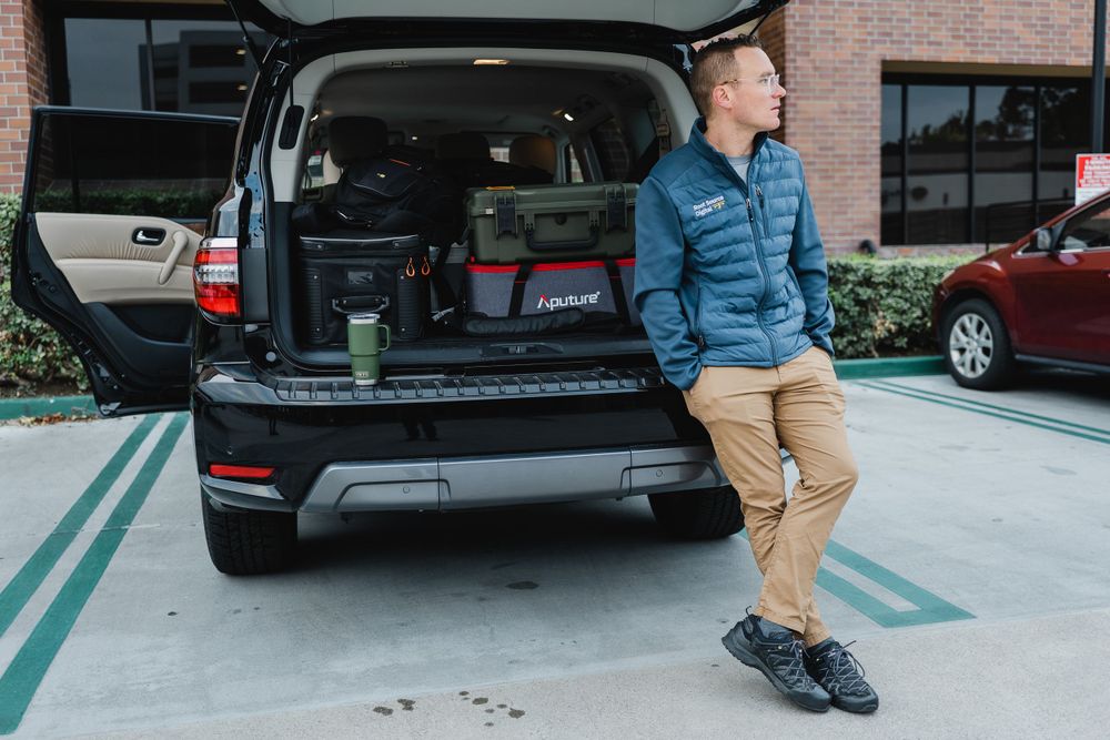 SUV with open trunk loaded with equipment in parking lot.