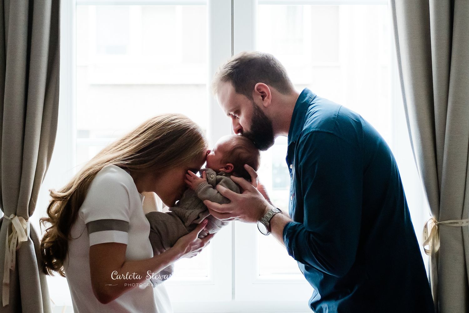 Mother and father kissing baby