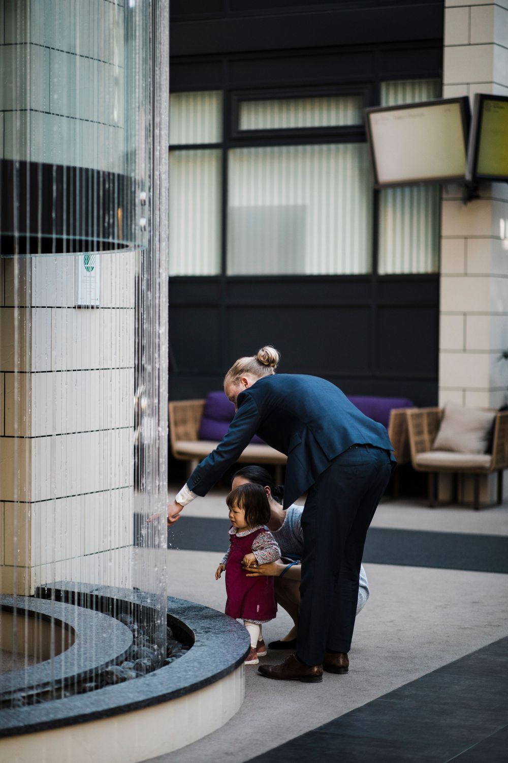 A tender moment by a modern water feature in an urban setting.