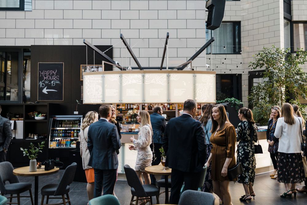 Wedding reception guests gathering under elegant lighting at an outdoor urban venue.