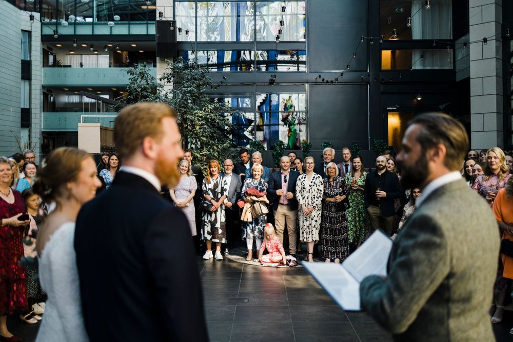 Guests gather in a modern indoor venue for a wedding ceremony.