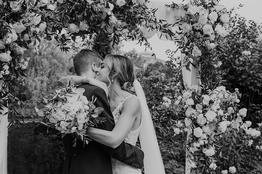 Bingham Riverhouse wedding photographs, emotional couple embrace under flower arch