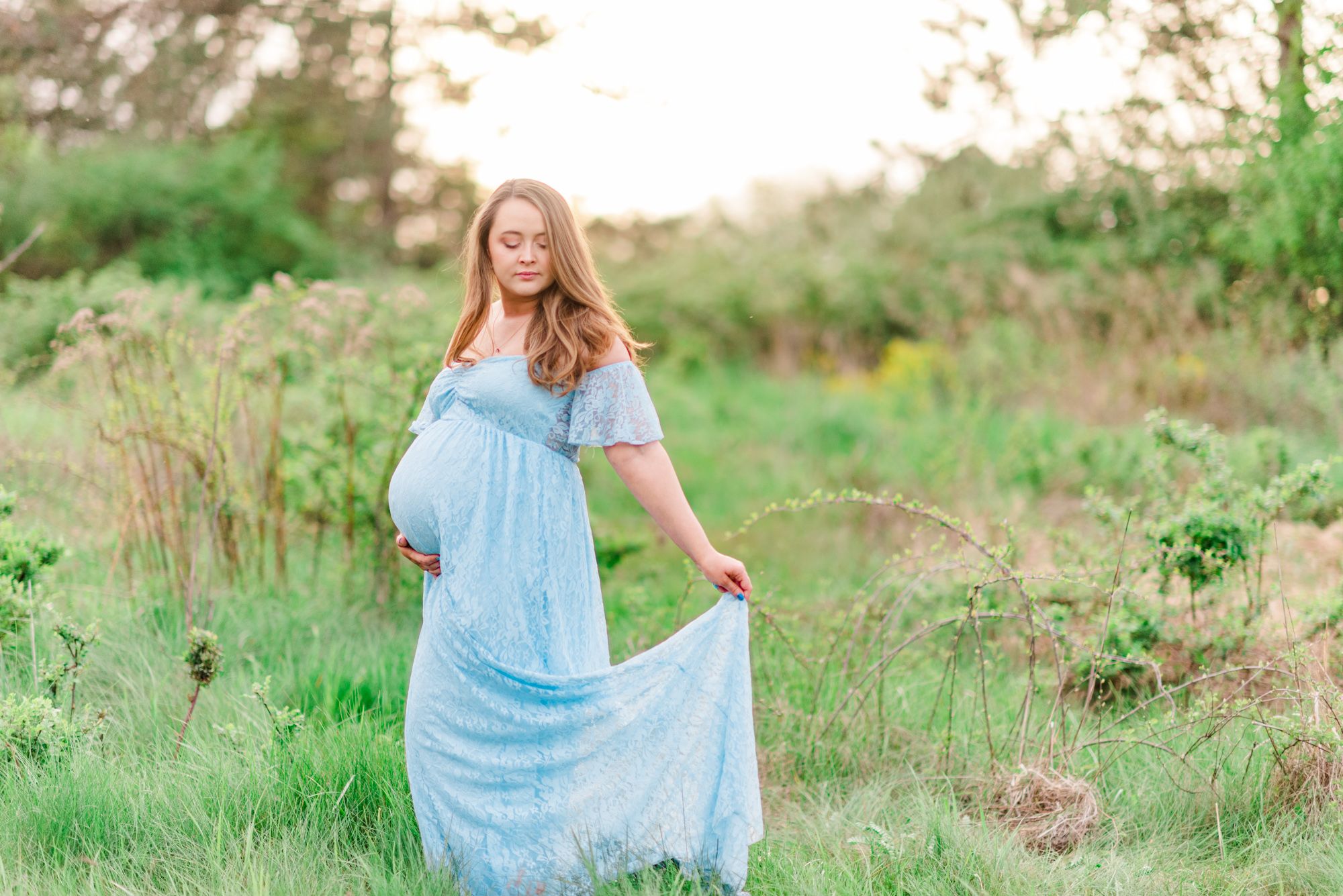 Maternity session with pregnant mother in field in golden hour sunlight at Moraine State Park, Pennsylvania