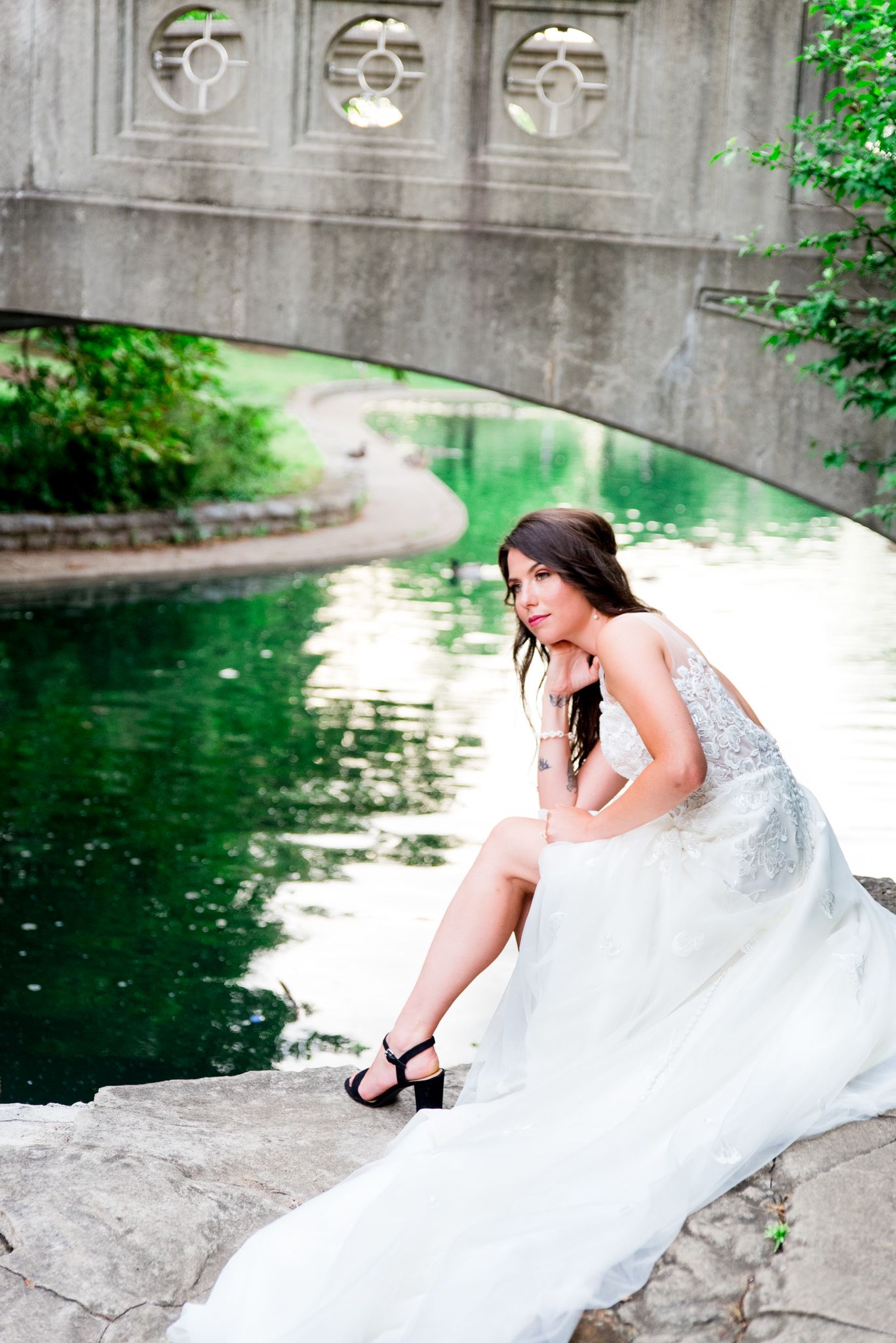 bride in Kelly faetanini Serafina gown sitting on rocks under bridge at Eden Park