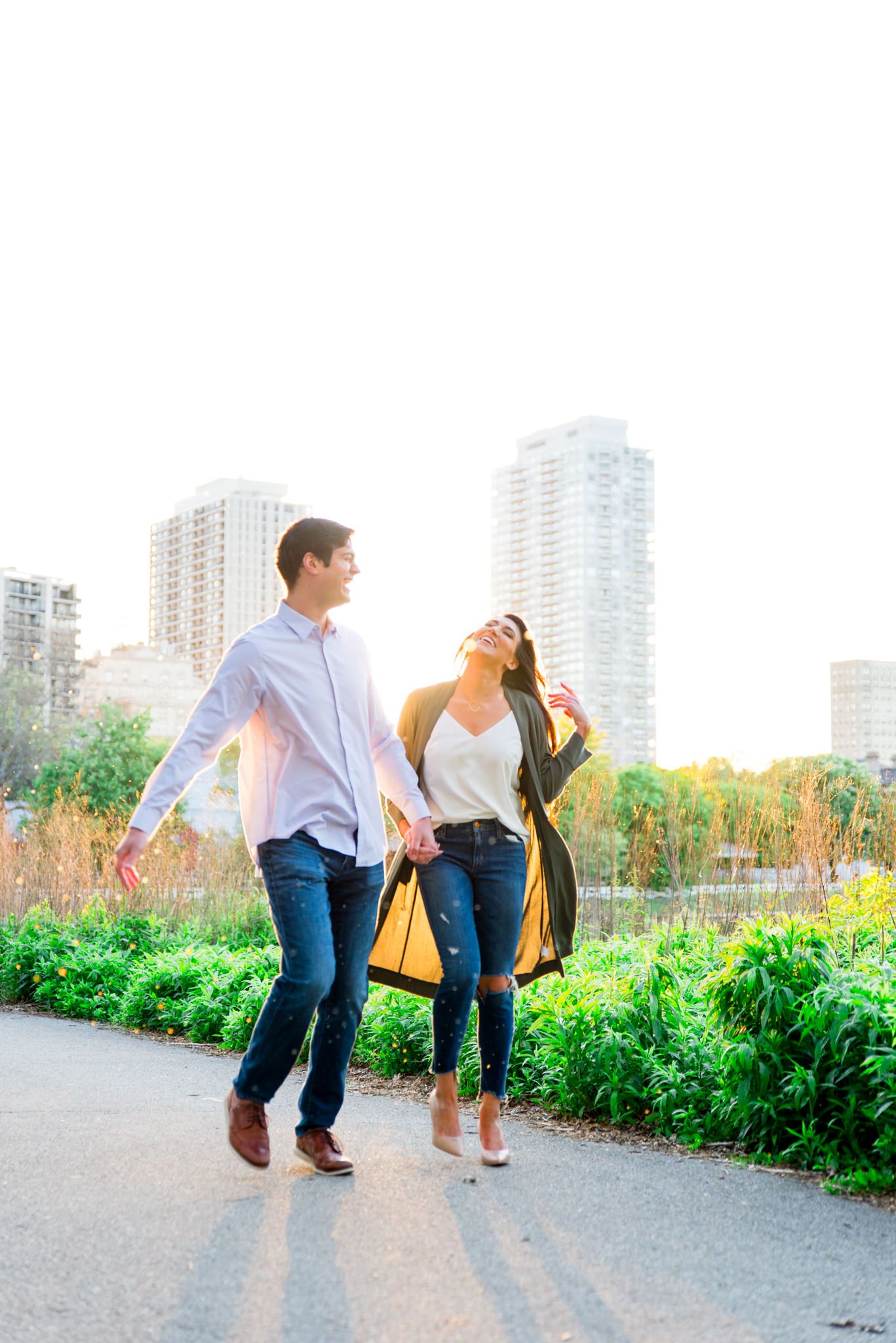 man and woman holding hands at sunset walking through Lincoln Park for engagement pictures in Chicago