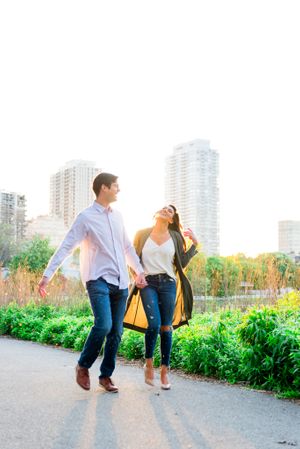 man and woman holding hands at sunset walking through Lincoln Park for engagement pictures in Chicago