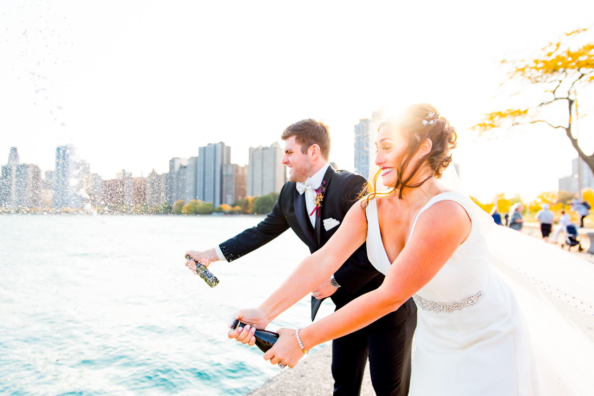 bride and groom pop champagne in front of lake michigan in chicago at North Avenue Beach