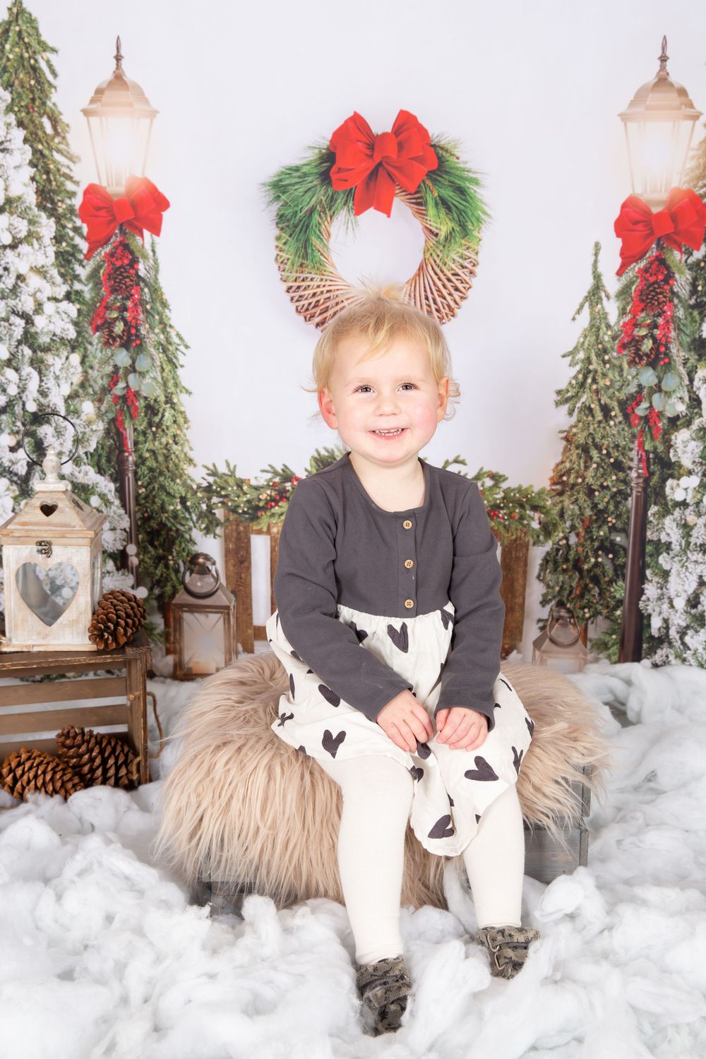 little girl sat on a fur crate in snow with trees in the background