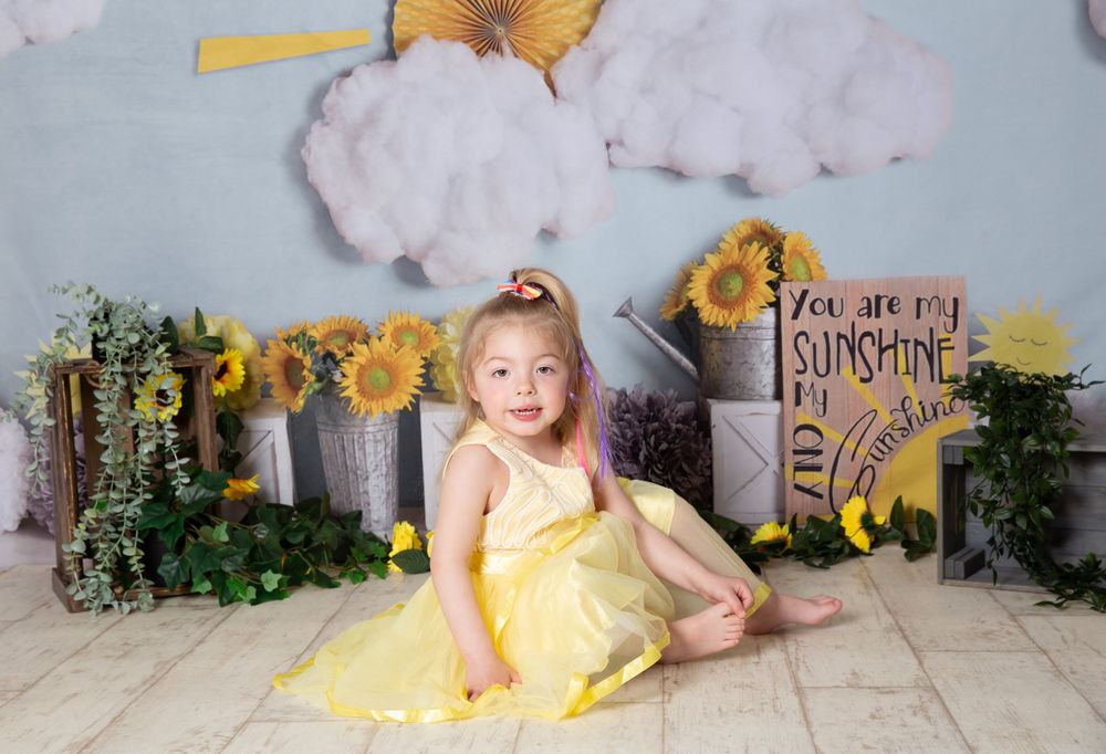 ittle girl in yellow dress with a sunshine background