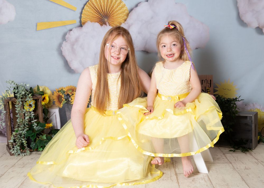 2 childing in yellow dresses with a sunshine background