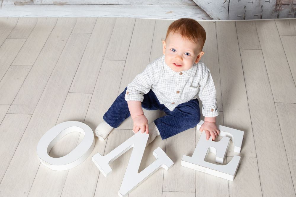 little boy looking up with one letters in his hands