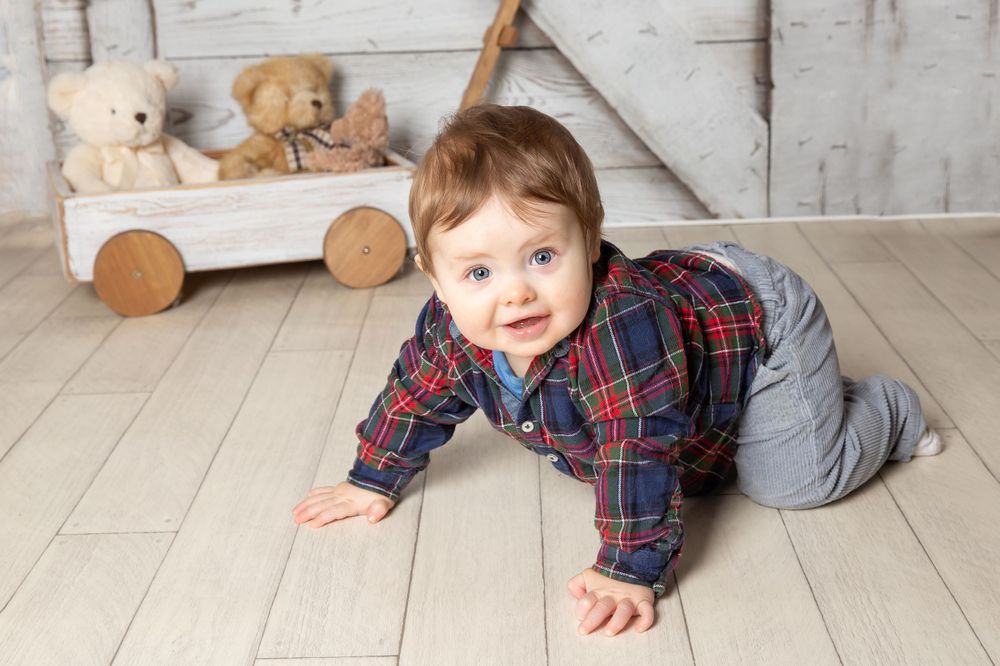 little boy crawling smiling with cart in background
