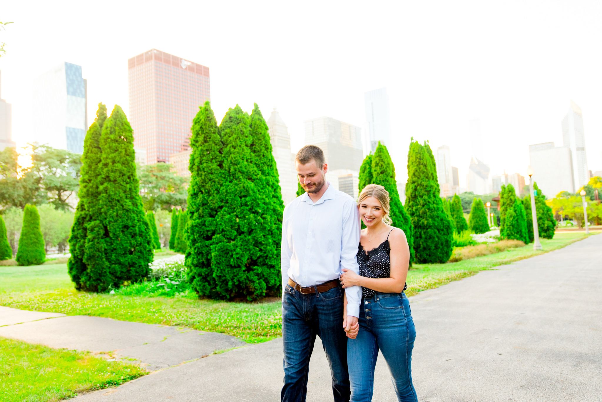 woman in tank top and jeans hugging man in white shirt and jeans in Millennium Park engagement pictures