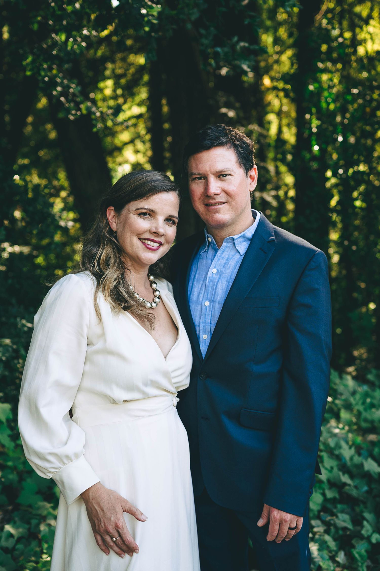 Bride in long sleeve wedding dress with groom in blue suit.