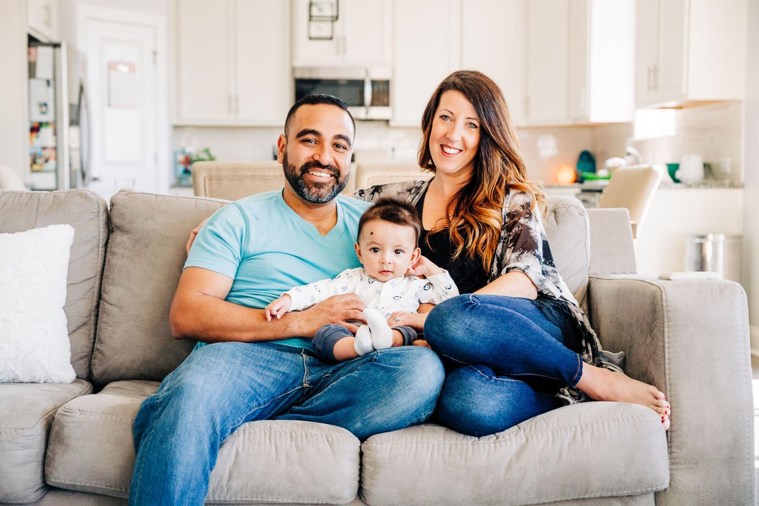 A Charlotte, NC family smiling at the camera while sitting on their living room couch