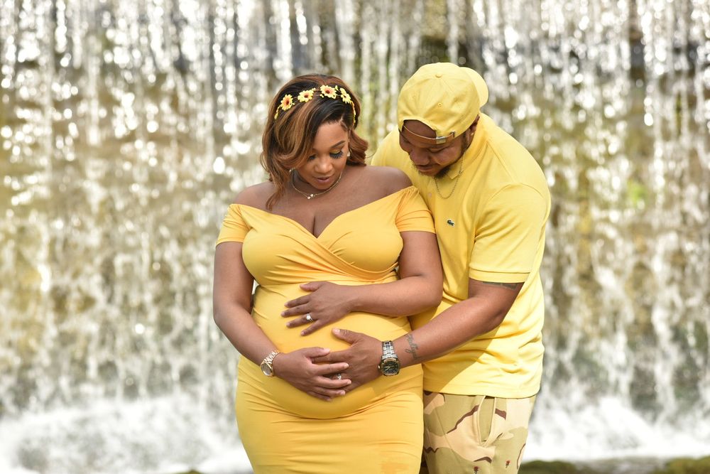 mother and father pose in front of waterfall+ buck creek+ Helena+maternity photo session + African American maternity
