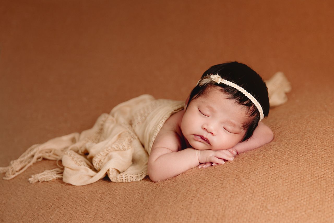 newborn sleeping chin resting on back of hands draped in boho scarf
