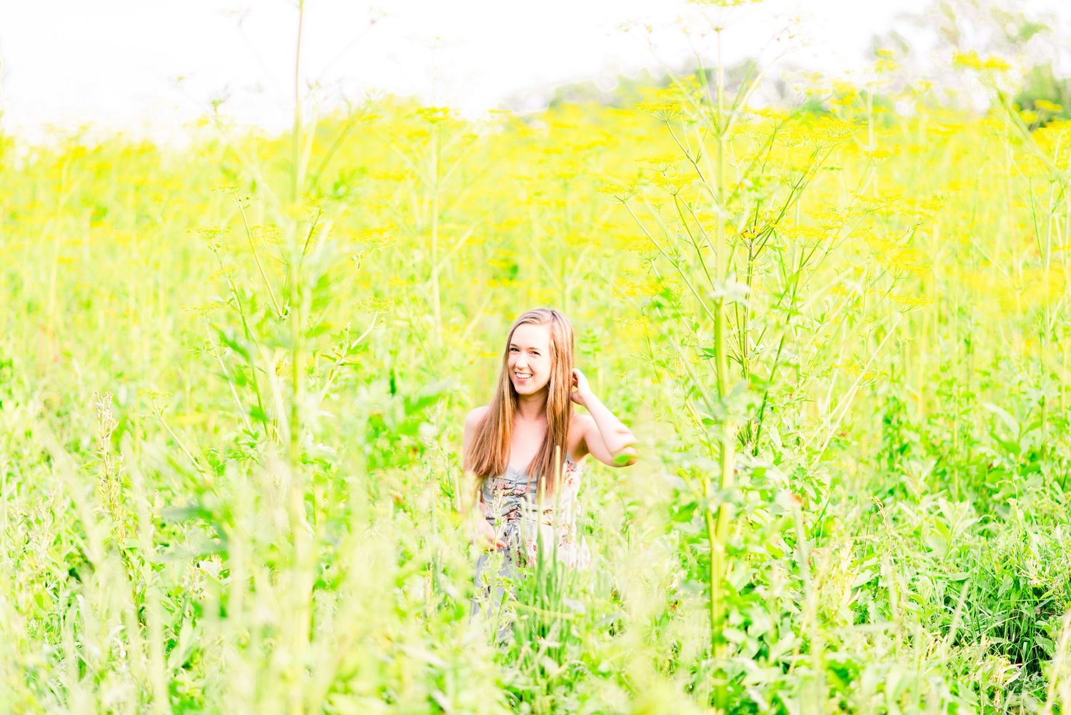 young woman standing in field of giant yellow flowers for summer senior pictures at Montrose Bird Sanctuary in Chicago