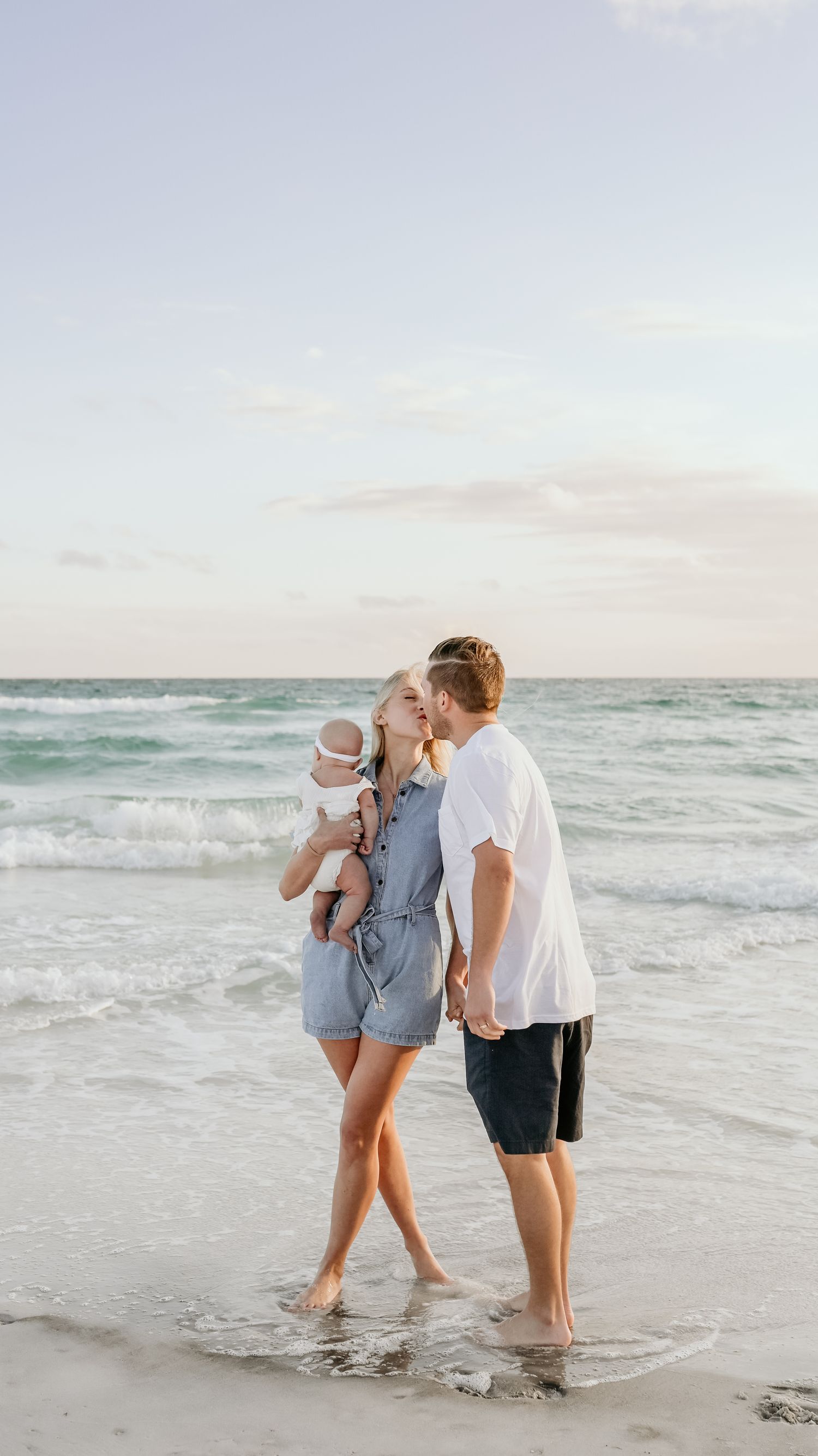 Family sharing a tender moment together on a beach at sunset with waves in the background.