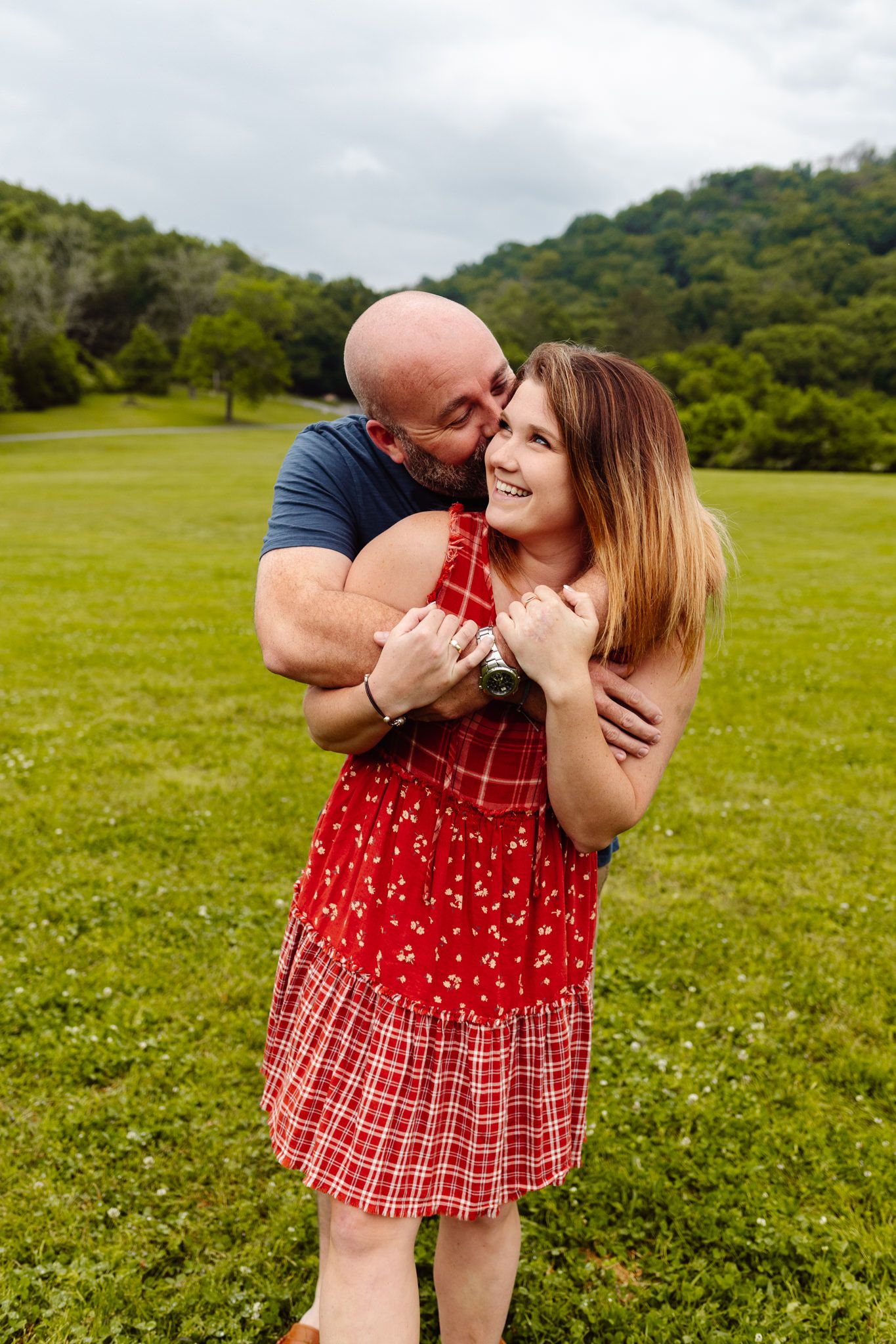 Woman in a red dress smiles up at her fiance during their Chattanooga engagement.
