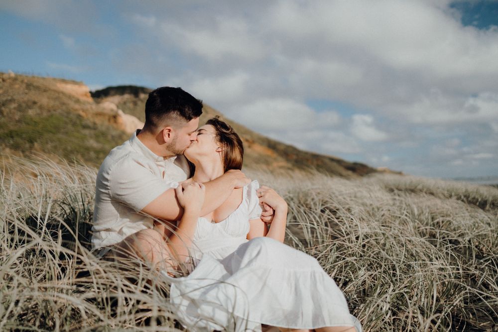 A tender moment shared between a couple amid wild grass on a hillside.