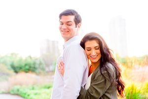 woman hugging man from behind with her eyes closed at sunset in a green jacket