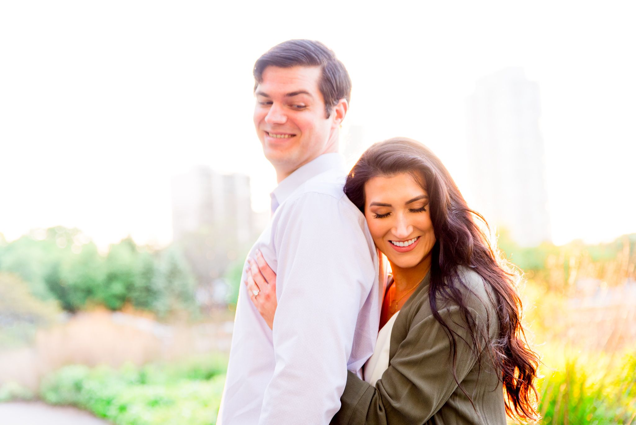woman hugging man from behind with her eyes closed at sunset in a green jacket