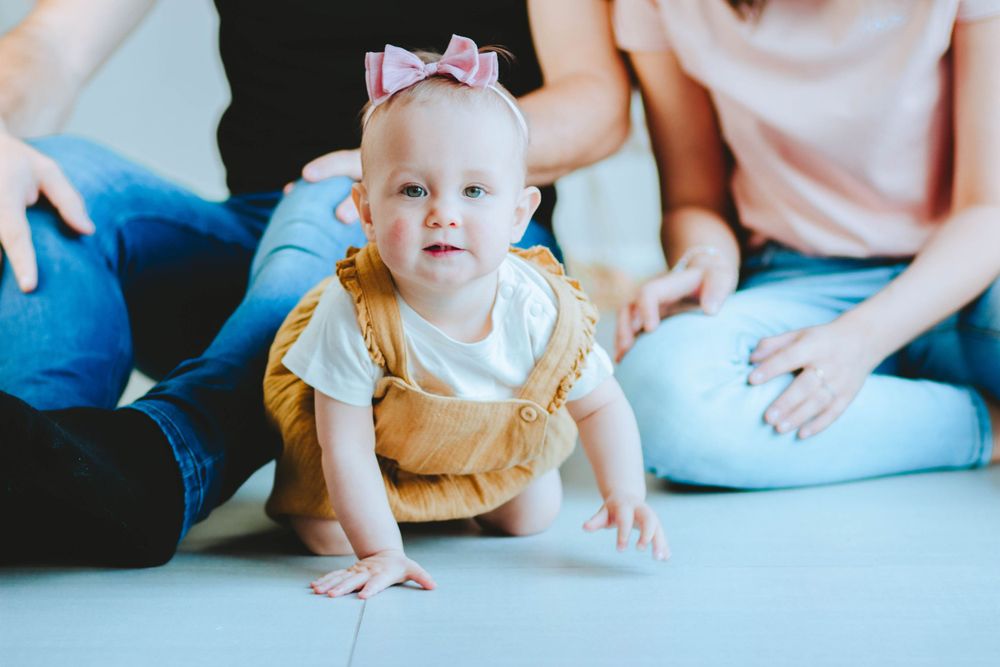 kruipend baby meisje met mama en papa op de achtergrond