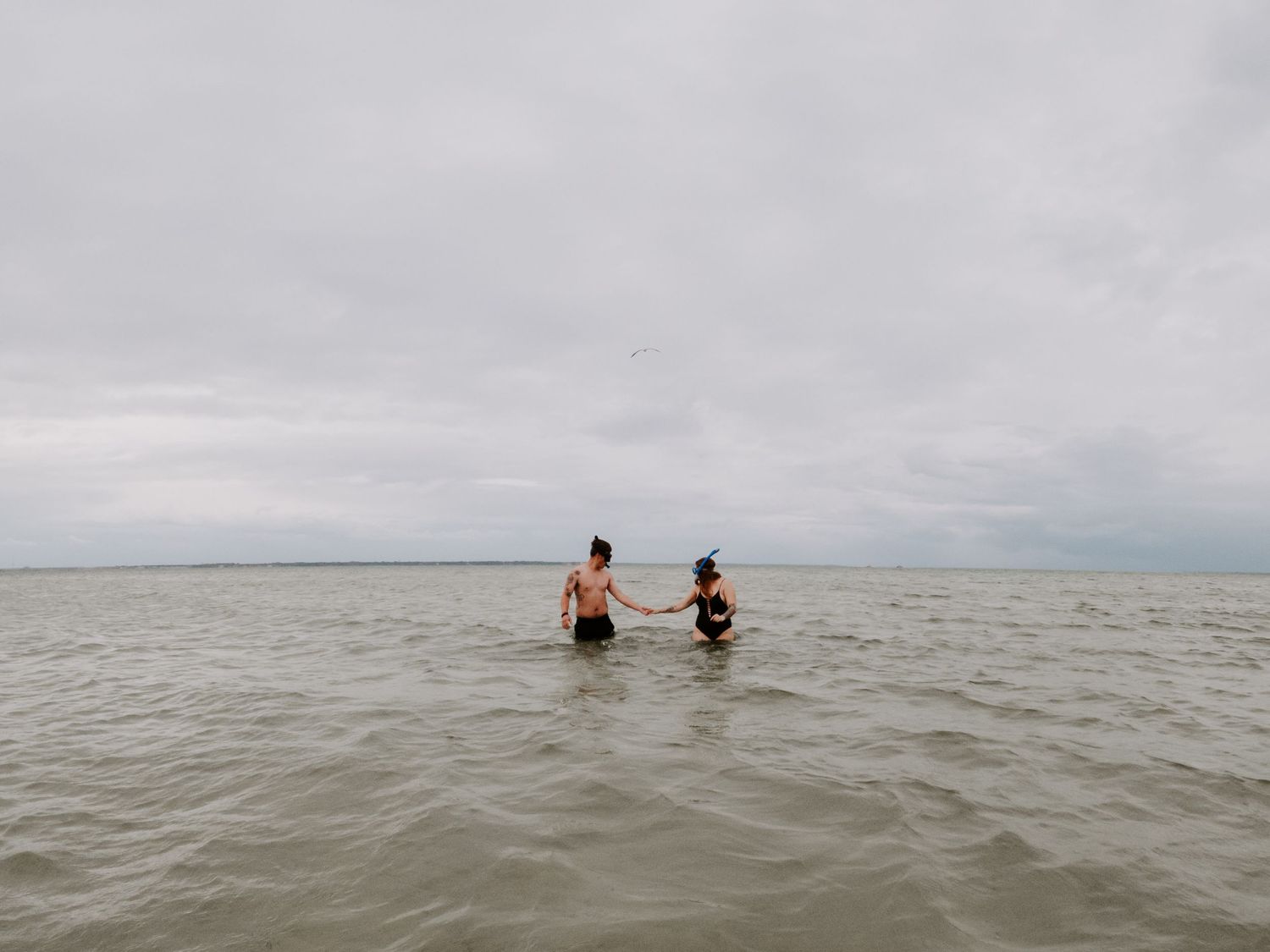 couple walking in the ocean with their snorkeling gear